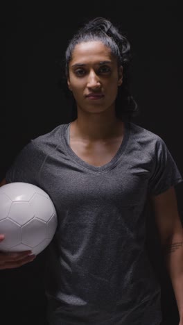 Retrato-De-Estudio-De-Video-Vertical-De-Una-Futbolista-Vestida-Con-Ropa-Deportiva-Sosteniendo-Una-Pelota